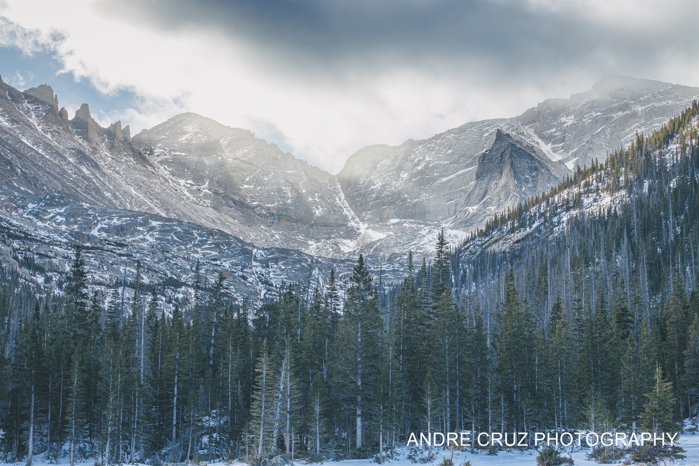 Jagged rock spires along the Continental Divide above a snow-covered forested basin in winter