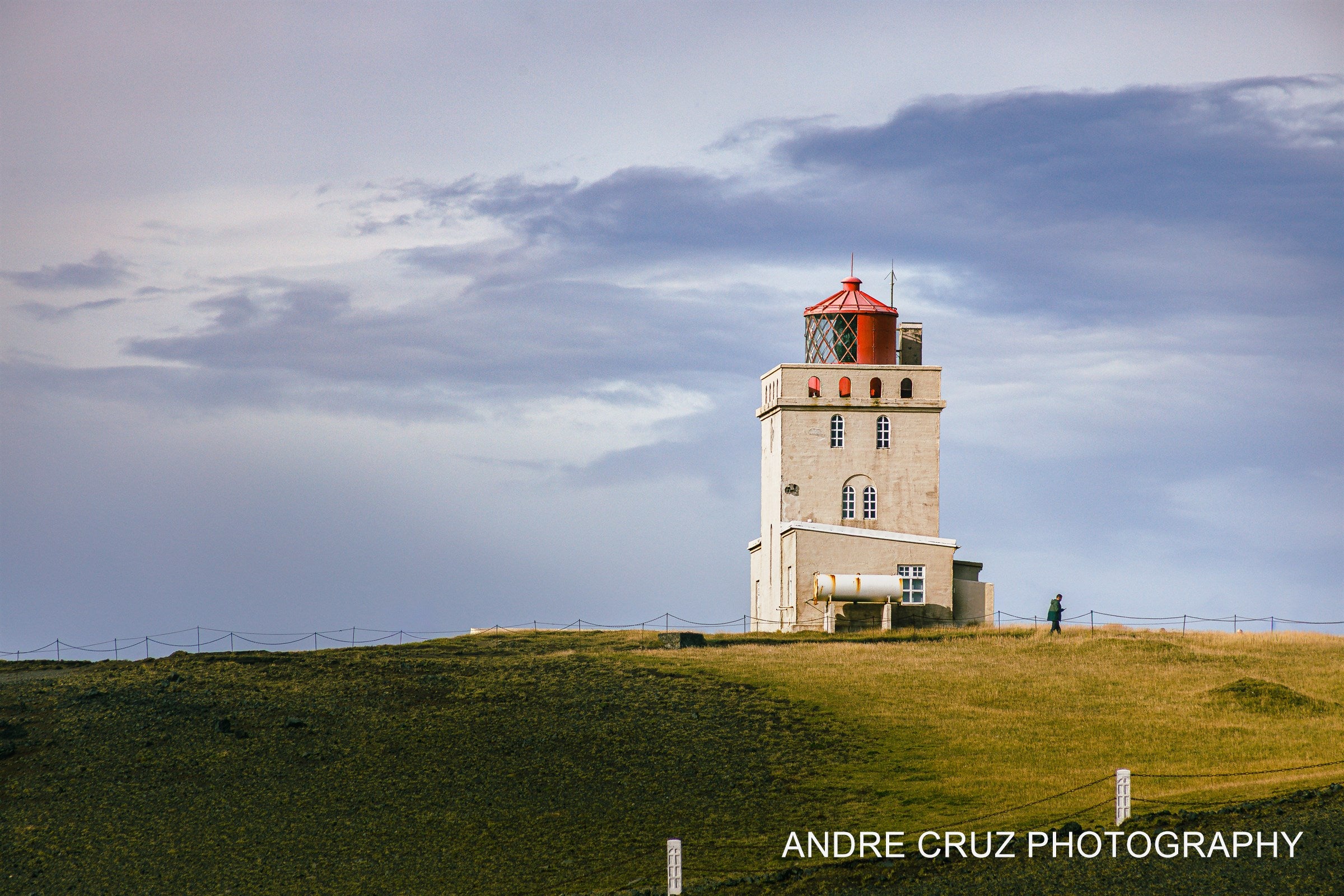 The Dyrholaey lighthouse on its green headland under a heavy sky, southern Iceland