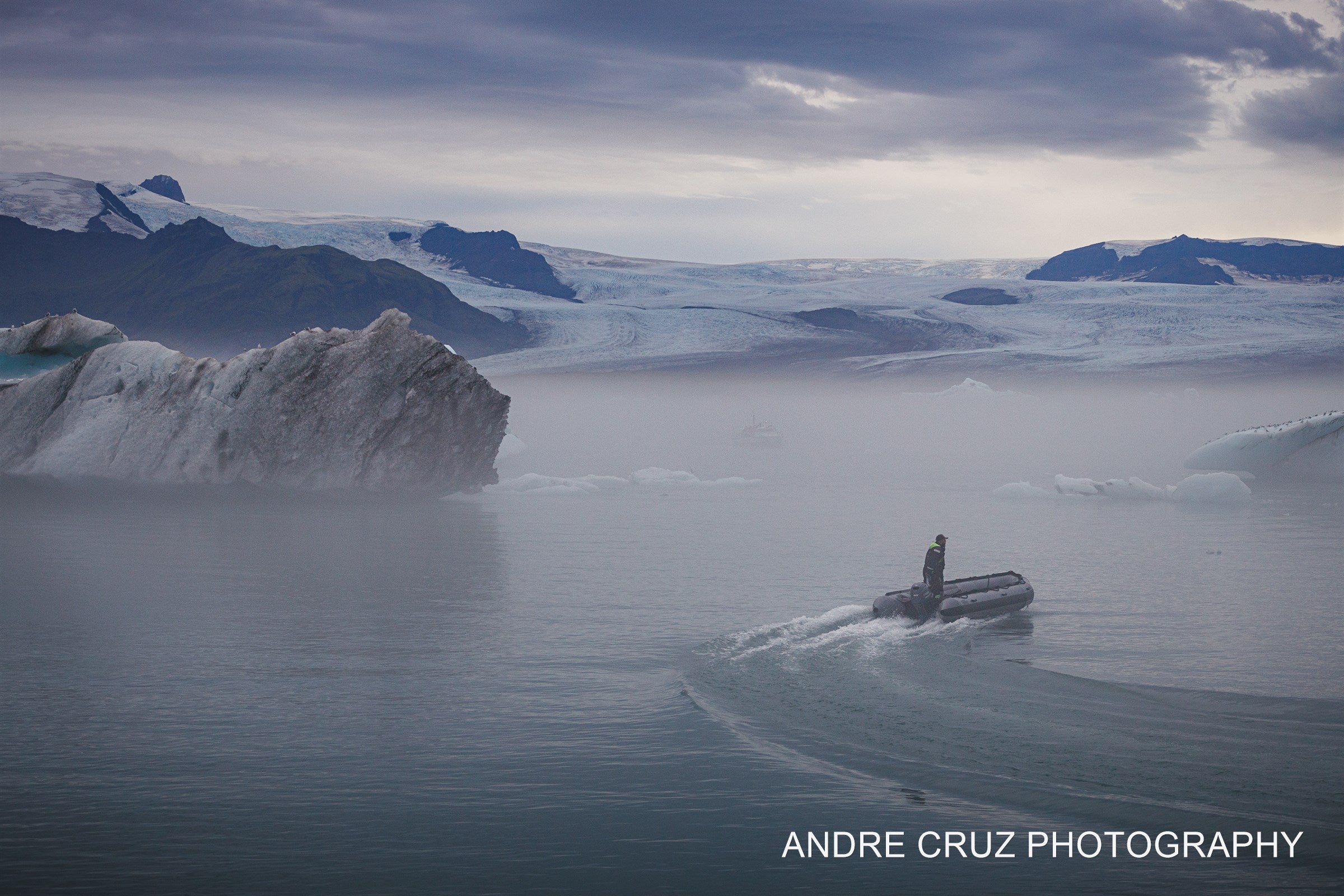 Icebergs drifting on the still water of a glacier lagoon under low cloud, Iceland