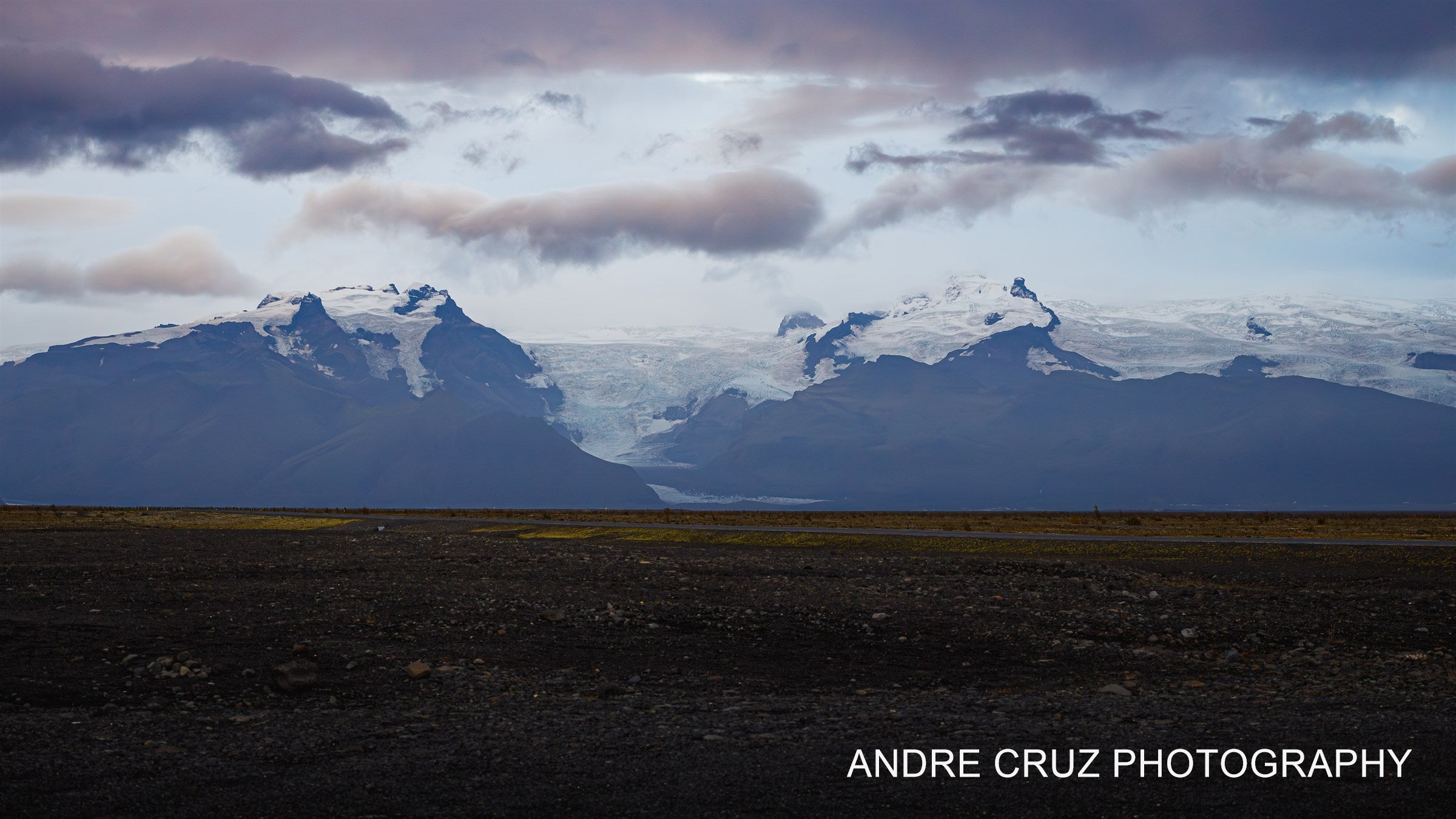 Wide glacial outwash plain with ice and dark volcanic sand under heavy cloud, Iceland