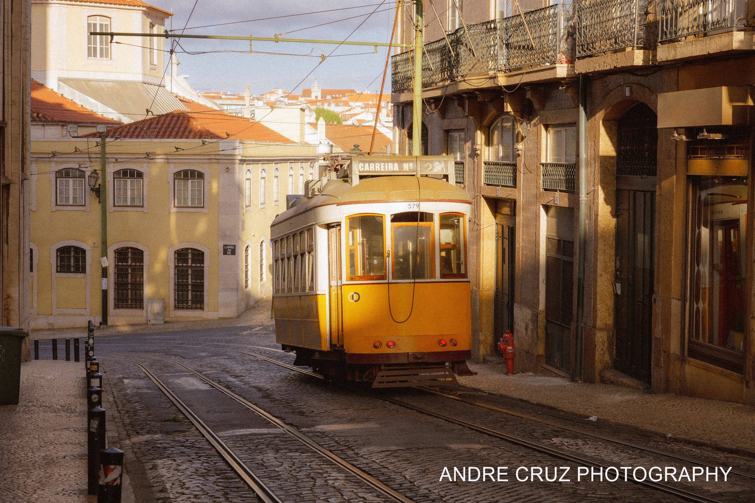 A yellow tram rounding a corner between pastel buildings in Lisbon, Portugal