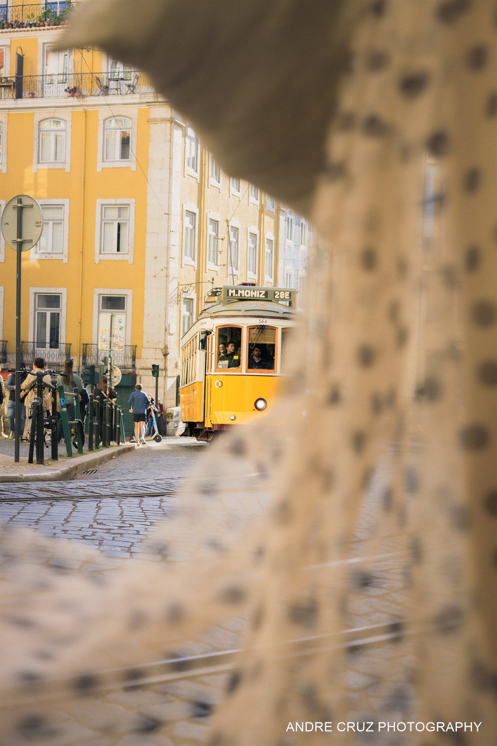 A yellow tram framed through a stone arch on a Lisbon street, Portugal