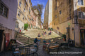 Stone staircase in the Alfama district of Lisbon with cafe tables and people sitting on the steps