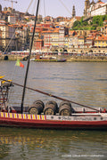 A traditional rabelo boat loaded with port barrels on the Douro river in front of the Ribeira, Porto